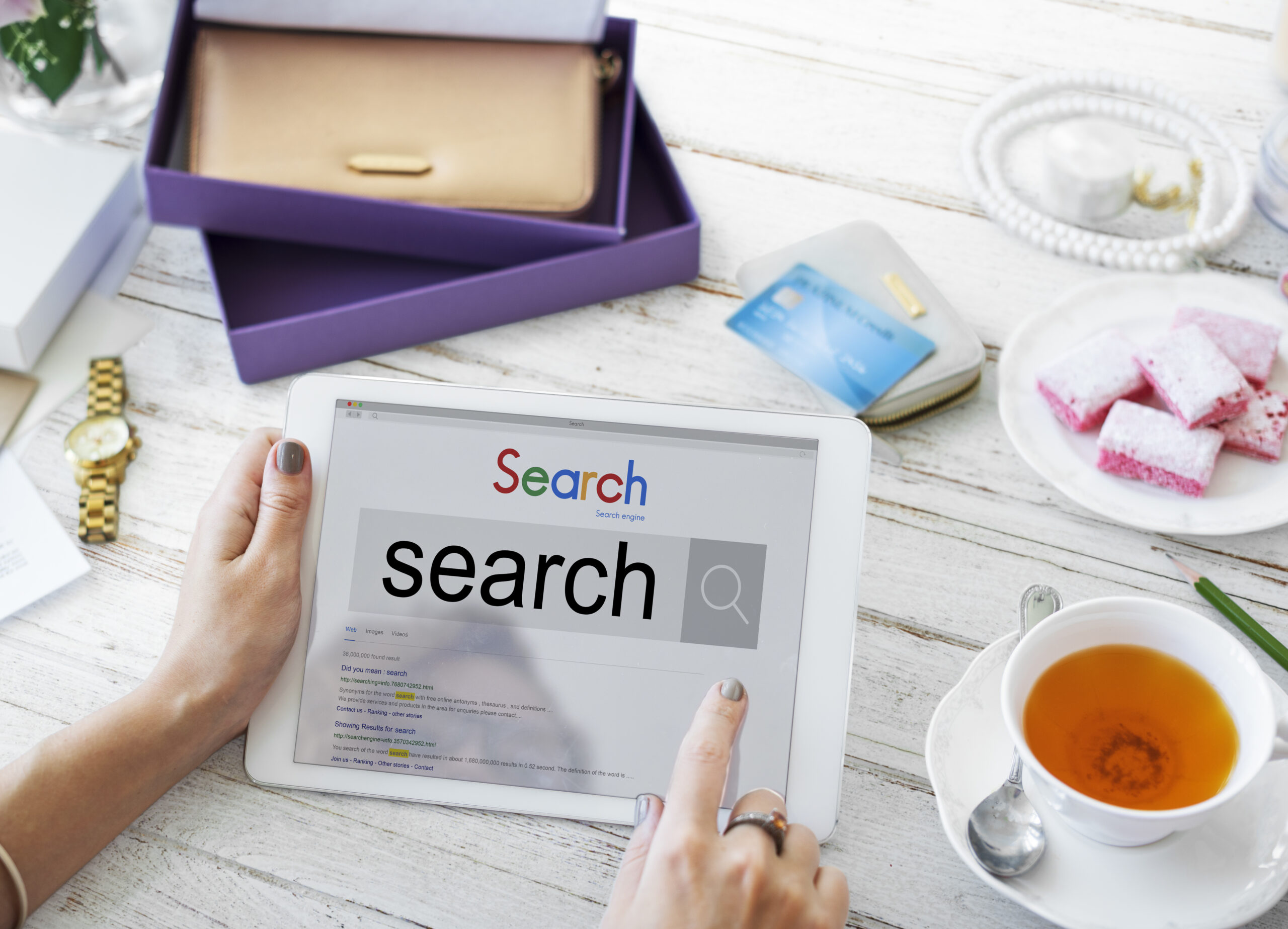 Person using a tablet to perform a search engine query for SEO research.