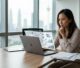 A Malaysian strategist plans content beside a laptop and research notes in a bright office.