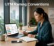 Marketer reviewing UTM campaign data on a laptop beside a notebook.