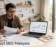 Architect reviews plans beside a laptop with search rankings in a bright studio.
